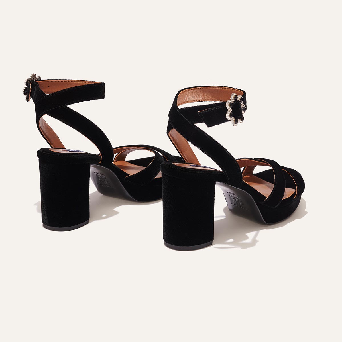 The Platform Sandal - Black Velvet by margaux-development features black velvet, thick heels, crisscross and ankle straps with decorative buckles, offering stylish comfort. Displayed on a plain light background.