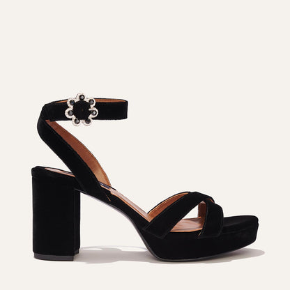 The Platform Sandal - Black Velvet by margaux-development is shown on a plain background, featuring a thick block heel for extra lift, crisscross toe strap, ankle strap with floral buckle and pearl accents.