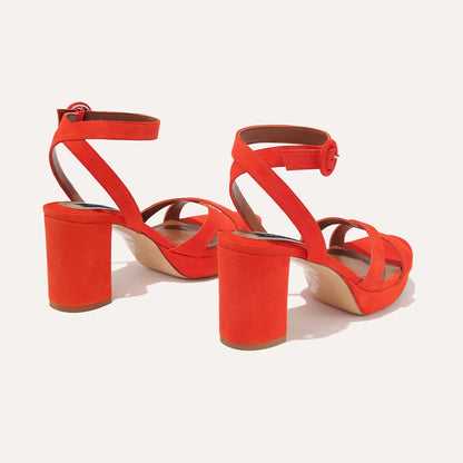 The Platform Sandal - Chili Suede by margaux-development features bold red suede, chunky heels, ankle straps with round buckles, and crisscrossed front straps, shown on a light background.
