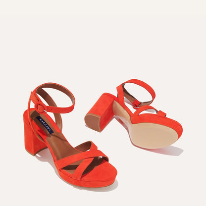 The Platform Sandal - Chili Suede by margaux-development: bright orange suede block heel sandals with ankle and crisscross toe straps, shown on a light background—one upright, one on its side to display the sole.