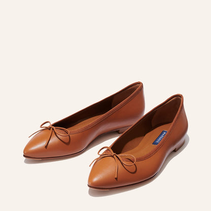 The Pointe in Saddle Nappa, a classic and comfortable ballet flat featuring a refined pointed toe design and decorative bow. 