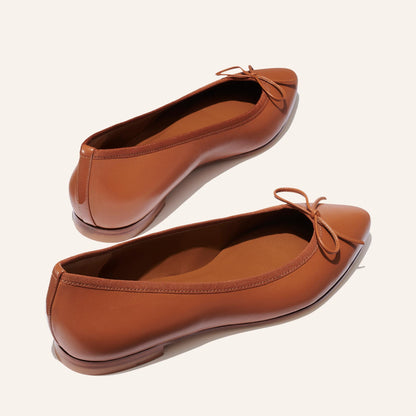 The Pointe in Saddle Nappa, a classic and comfortable ballet flat featuring a refined pointed toe design and decorative bow. 