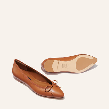 The Pointe in Saddle Nappa, a classic and comfortable ballet flat featuring a refined pointed toe design and decorative bow. 