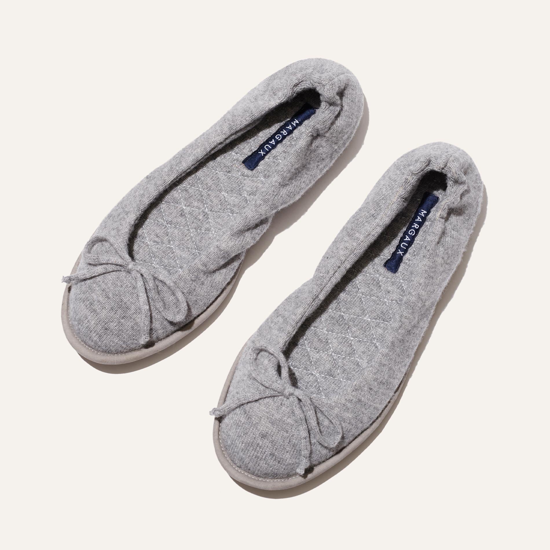 The Slipper - Heather by Margaux are gray quilted ballet flats with bow details, a plush quilted innersole, and dark blue insoles featuring the Margaux brand name in white.