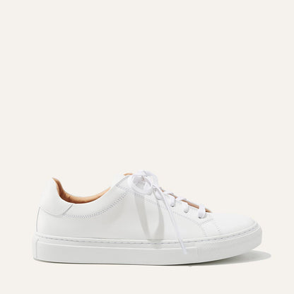 The Sneaker - White Calf by margaux-development is a white low-top sneaker with white laces and a thick rubber sole, shown in profile against a plain, light background.